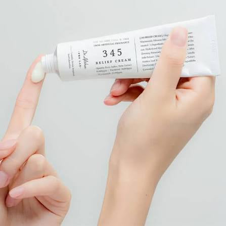 Hand holding a tube of 345 Relief Cream against a light gray background