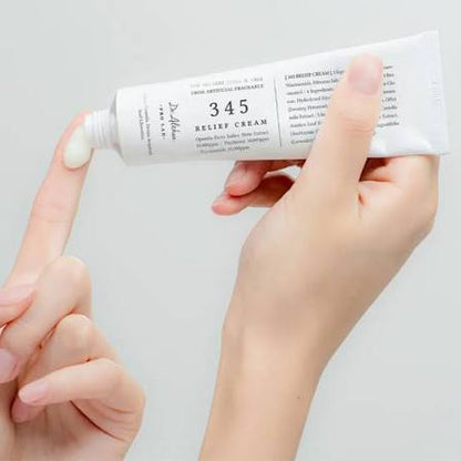 Hand holding a tube of 345 Relief Cream against a light gray background